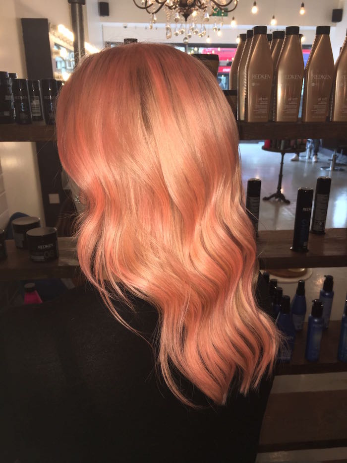 Shiny peach hair at Brixton salon in London against product display